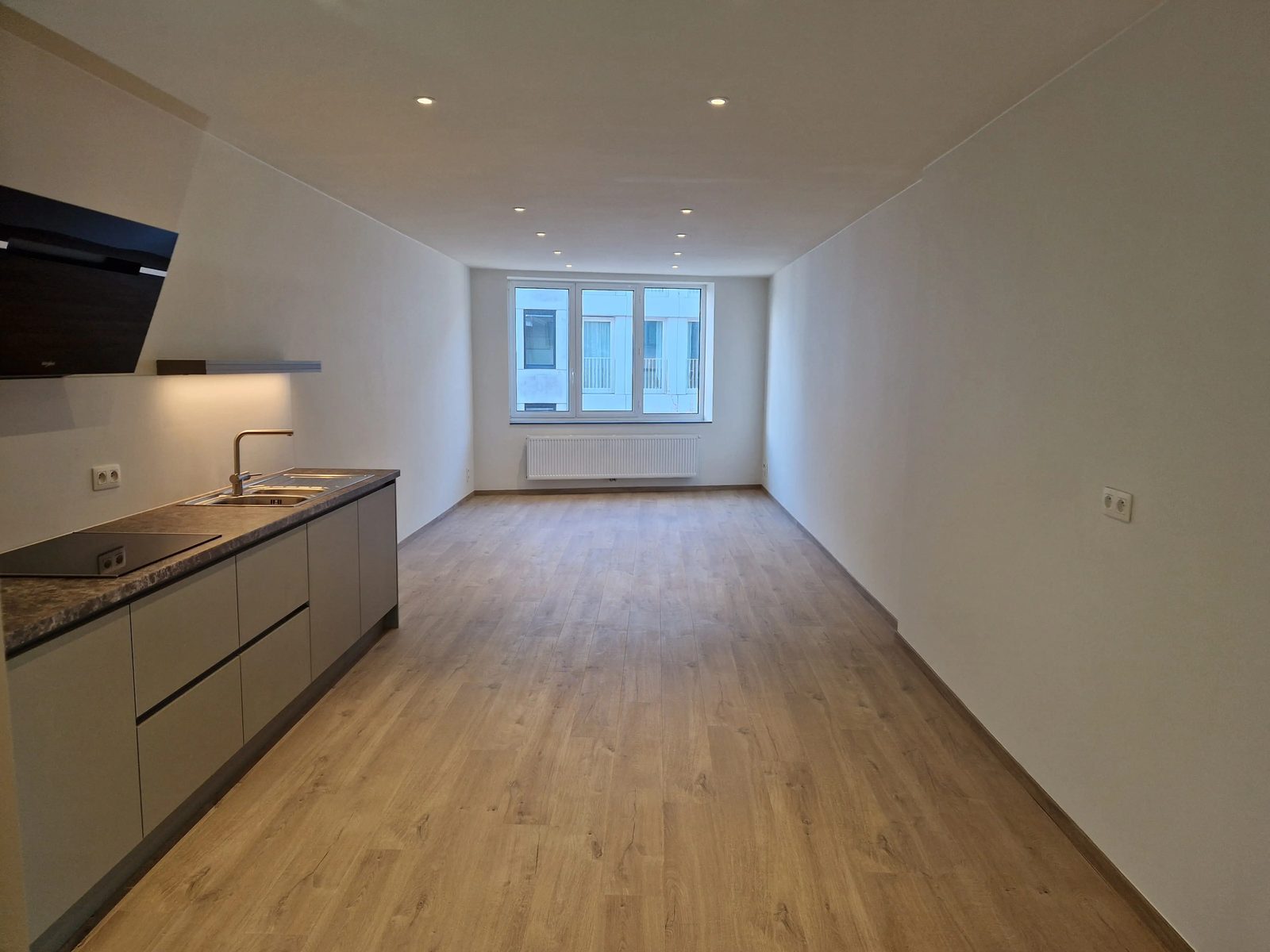 Woonkamer met zicht naar het raam van het gerenoveerde appartement op het Antwerpse Zuid
