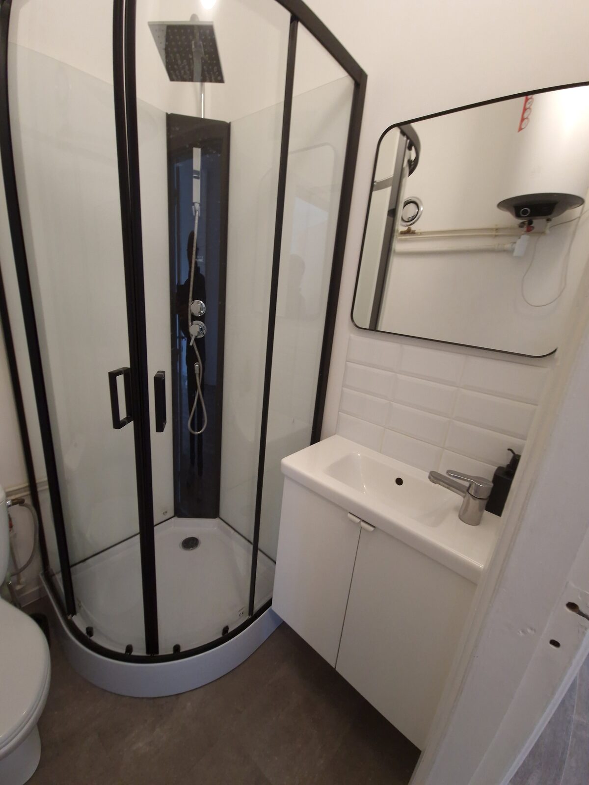 Douchecabine en lavabomeubel in de badkamer van de gerenoveerde studio
