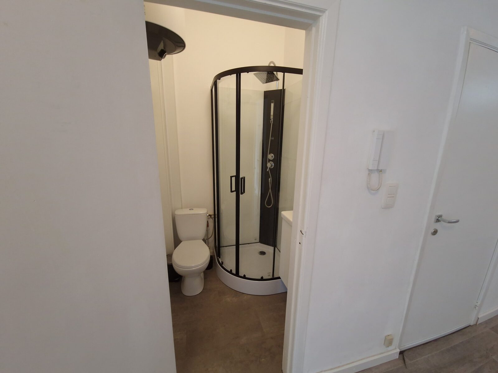 Doorkijk naar de badkamer met de parlofoon aan de muur van de studio in Antwerpen